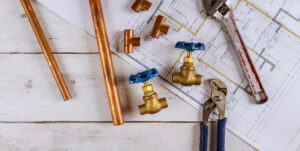 plumbing tools and pipes set on a blueprint of house